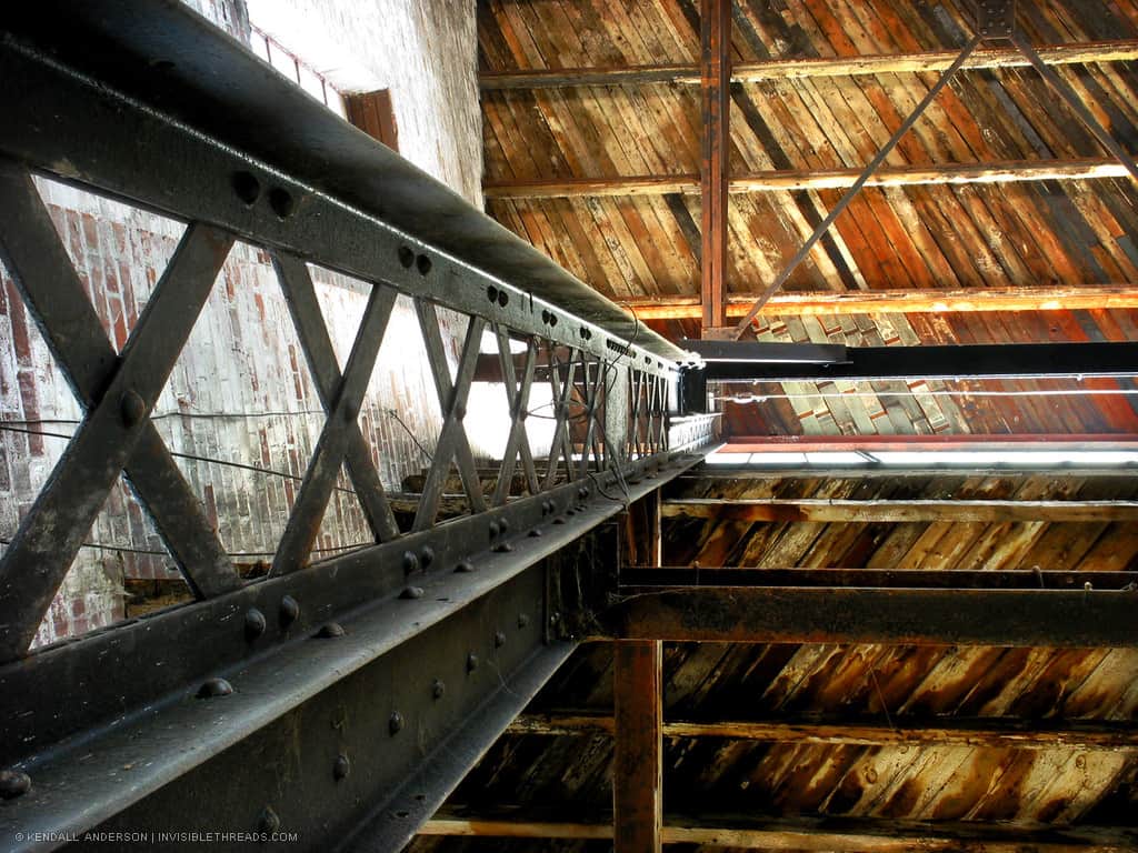 Standing beside a steel column, looking up towards the underside of a wood slat roof in an old warehouse