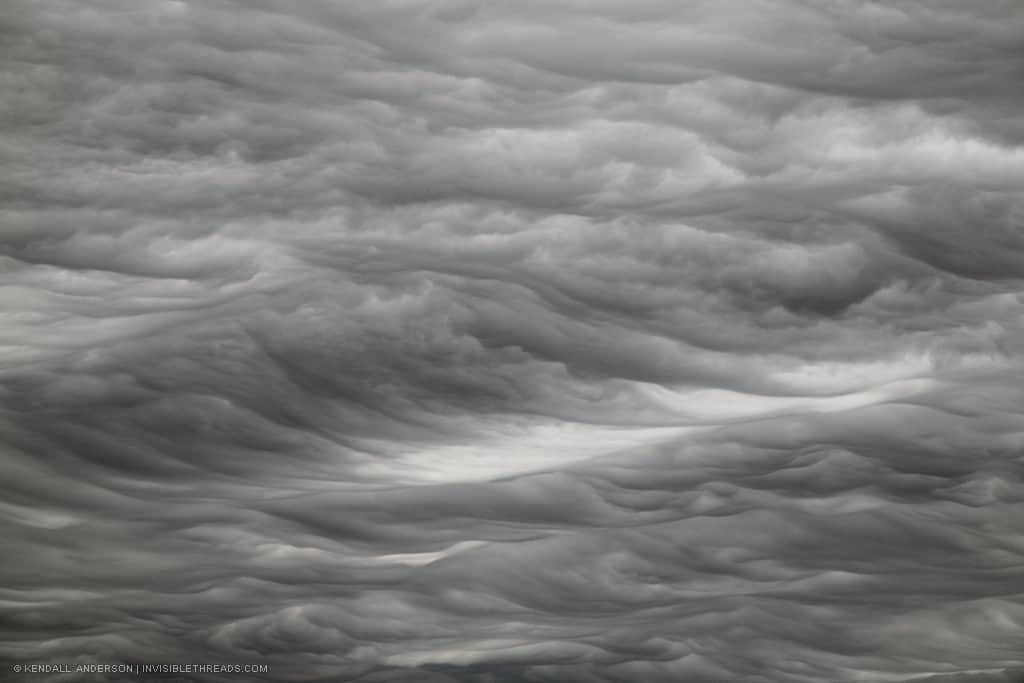 The sky is filled with misty cloud patterns that appear like rolling waves of smoke.