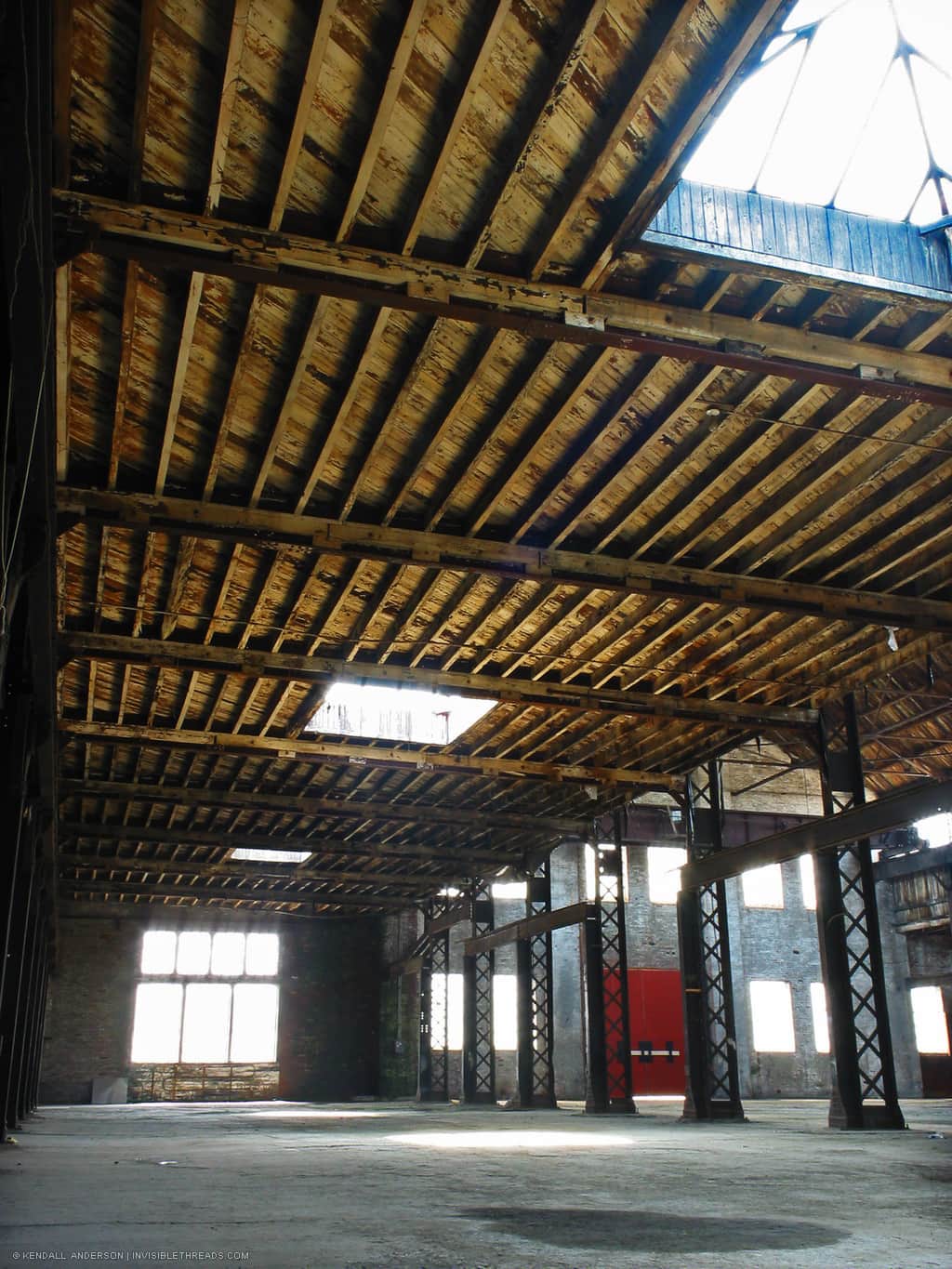 Wood joists holding up ceiling of industrial warehouse, with skylights