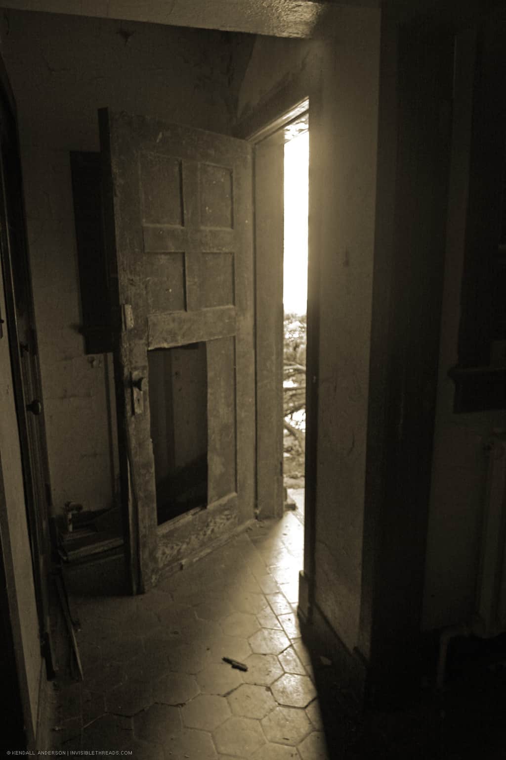 A door with a broken panel is open, leading to the outside.