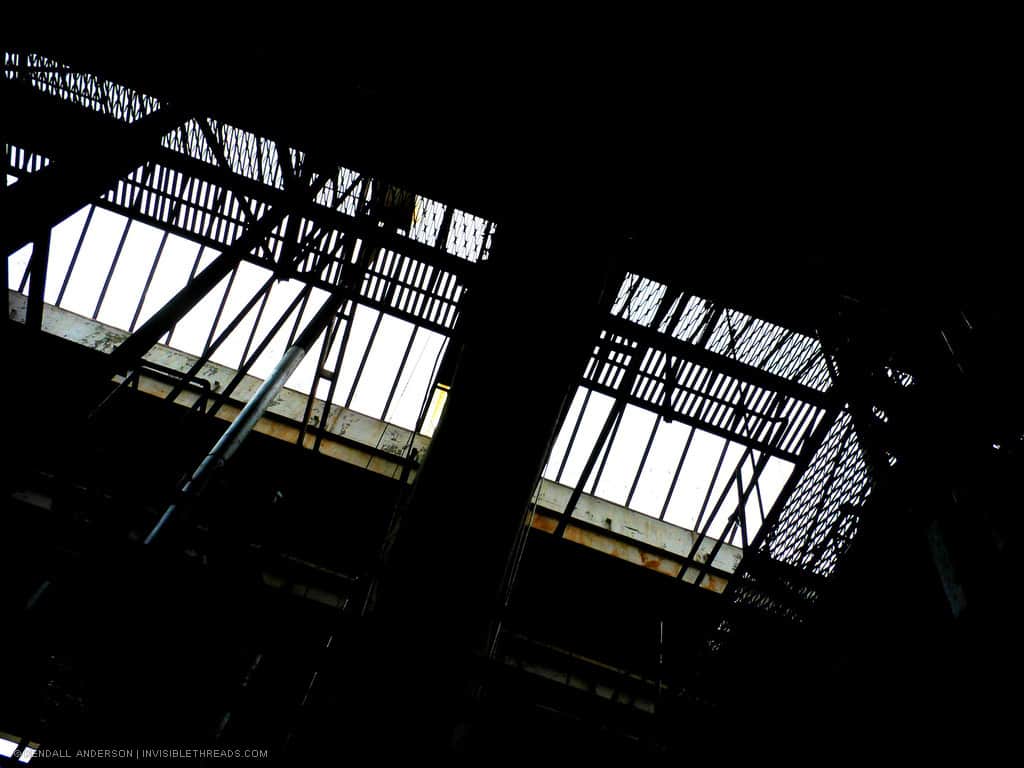 The overhead skylights show the silhouetted beams above a dark mechanical room.