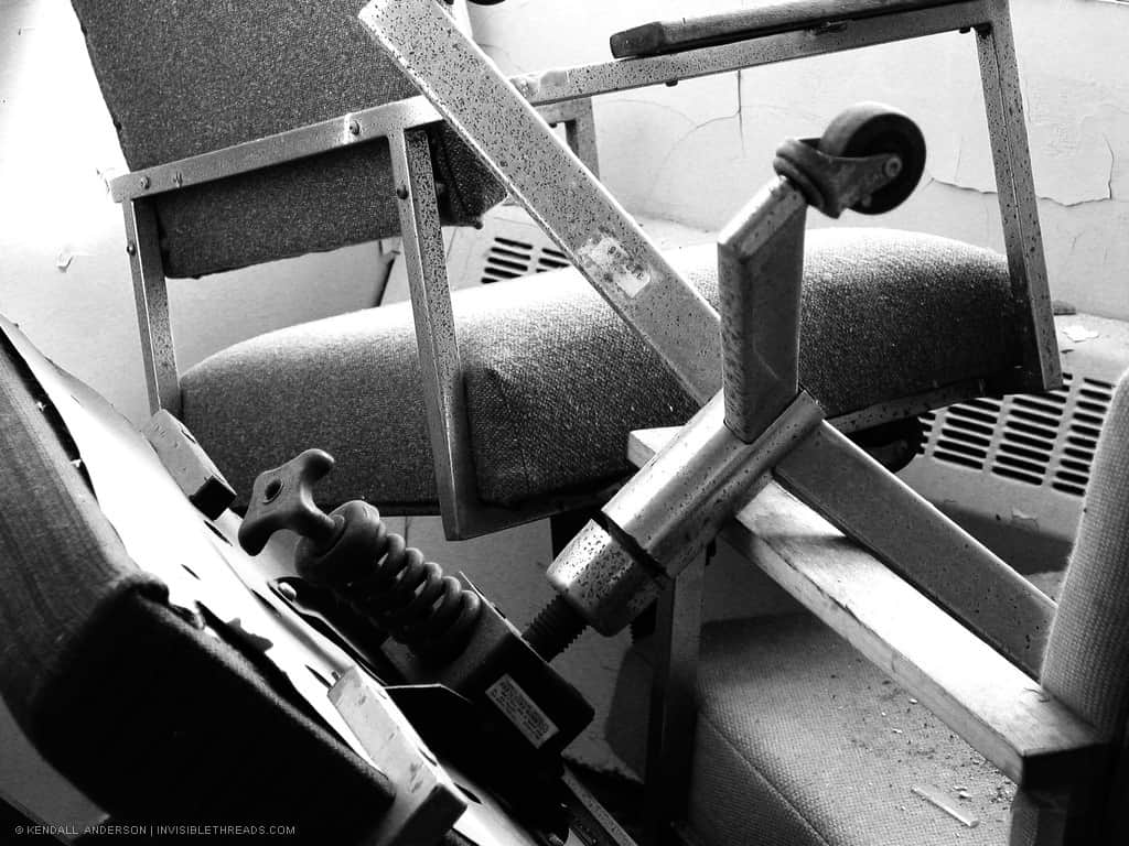 A few office chairs are overturned and stacked on each other.