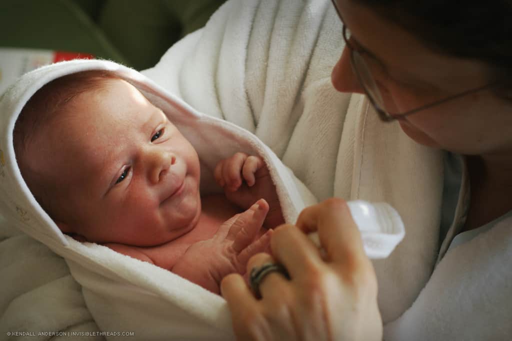 Mother holding and looking at swaddled baby