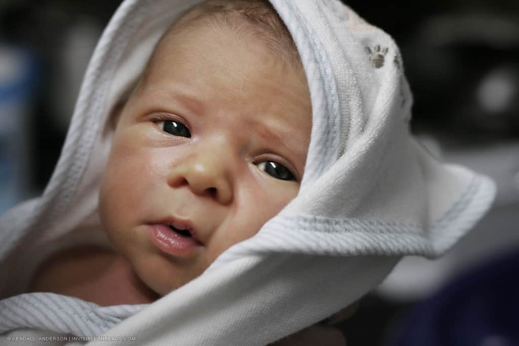 Portrait of a baby looking at the viewer, with a blanket wrapped around his head