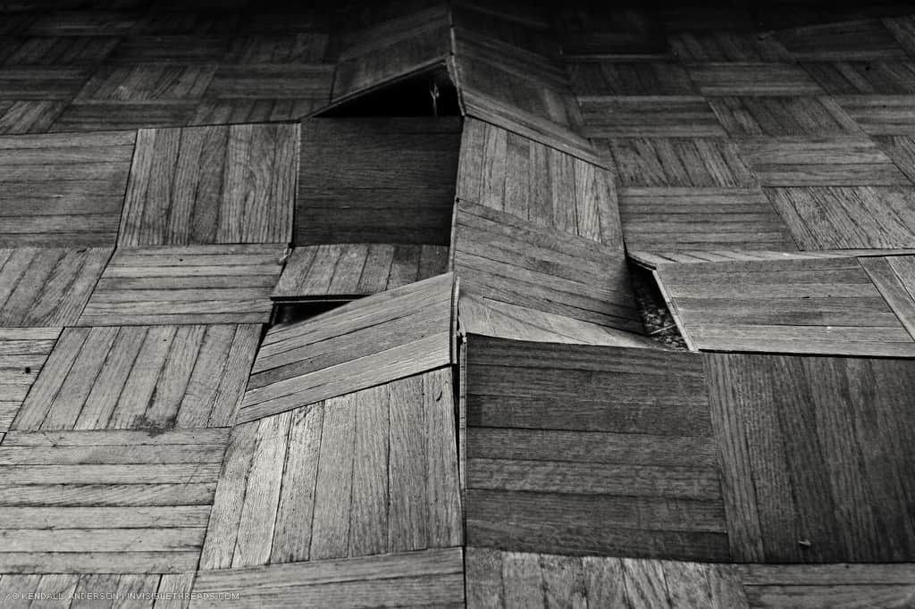 A pattern of parquet wood flooring buckling up due to expansion from water damage
