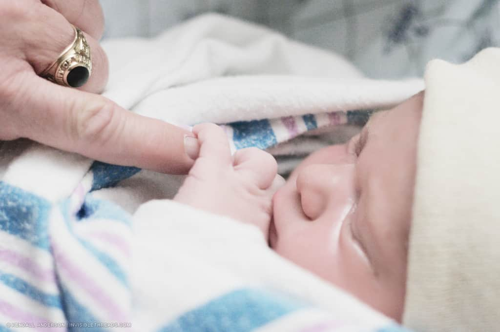 Sleeping baby holding an adult's fingertip