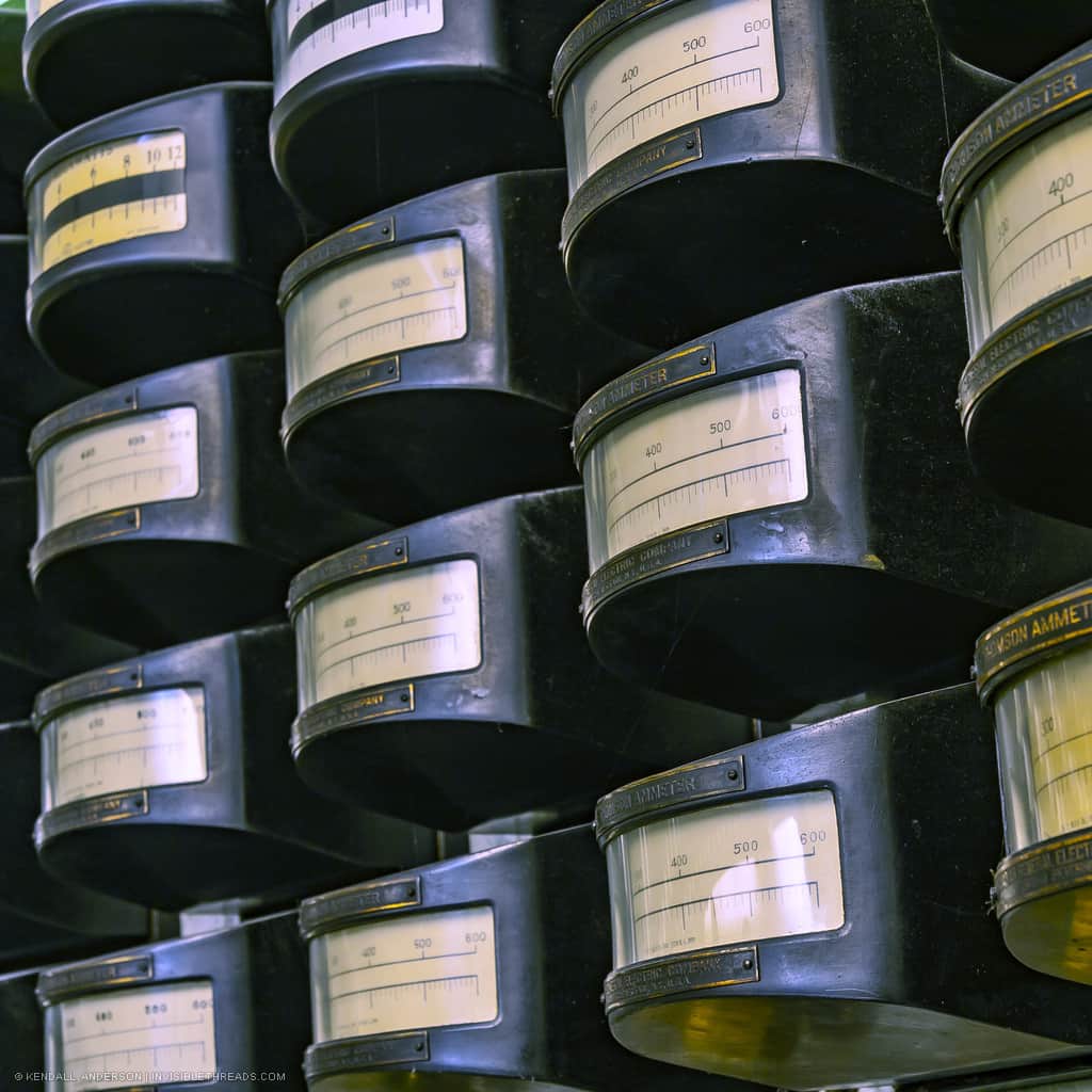 A collection of almost 16 Thomson Ammeters are arranged in rows and columns. These are used to measure the current in a circuit.