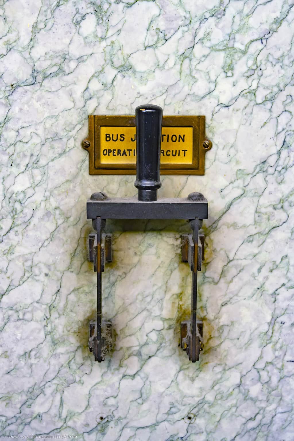 A large lever switch is mounted on a white marble panel. There is a yellow label behind the switch that reads 'Bus Junction Operation Circuit'.
