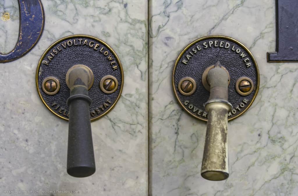 Two handles are mounted on a marble panel. The handle on the left is labelled 'Raise/Lower Voltage' and the handle on the right is labelled 'Raise/Lower Speed'.