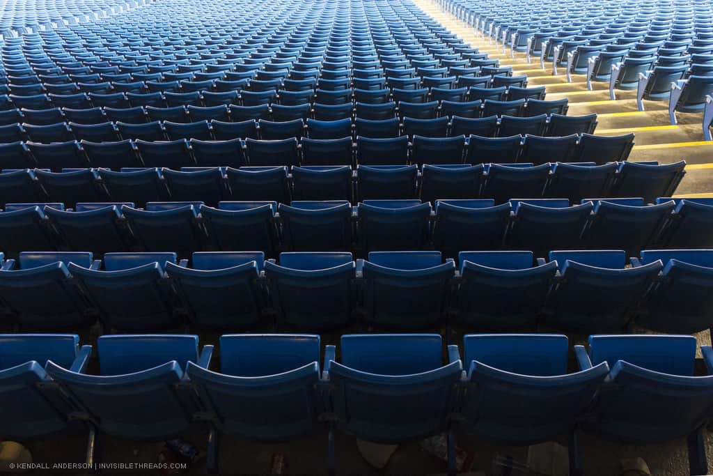 Hundreds of blue baseball bleacher seats from above and behind, all empty, as a regular grid pattern
