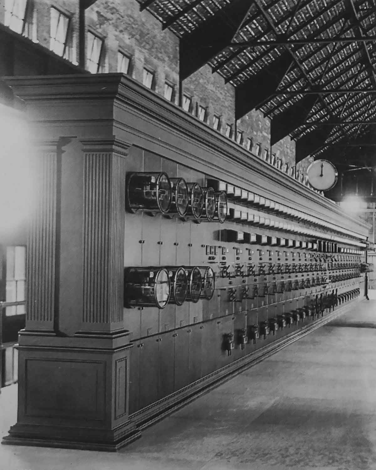 Archival photo from 1908 showing a bank of operating controls, dials, gauges and switches. Everything is mounted in a long wooden cabinet.